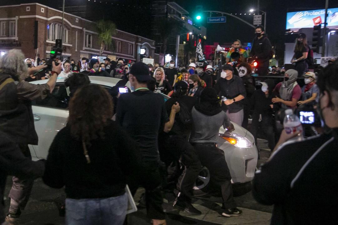 A Prius runs through a crowd of people on Sunset Boulevard and North Cahuenga Boulevard during a protest held for Breonna Taylor in Hollywood. (Josie Norris/Los Angeles Times)
